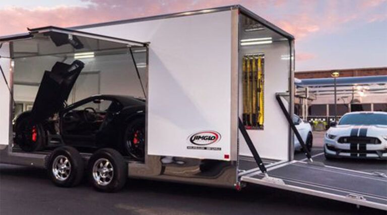 luxury cars getting loaded into an enclosed carrier